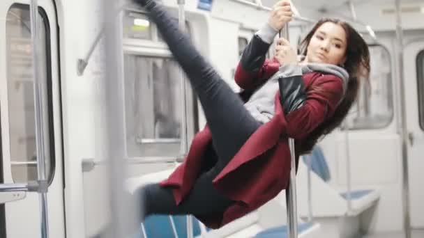 Молодая женщина впитывает танцы на шесте в движущемся поезде — стоковое видео