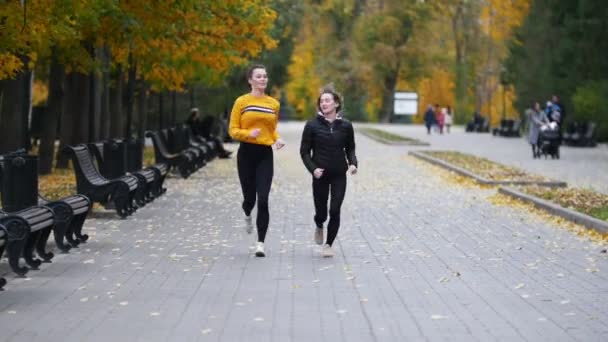 Young passen vrouwen uitgevoerd op stoep in herfst park. Lopend naar de camera — Stockvideo