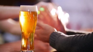 Erkek arkadaşları üzerinde arka plan bira içiyor. Tam bir bardak bira odak
