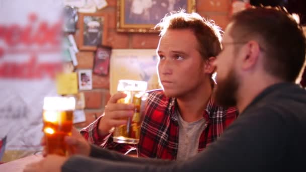 Dos tipos se sientan en el bar, bebiendo cerveza y hablando — Vídeos de Stock