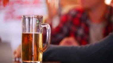 Yarısı boş bir bardak bira odak. Arka plan konuşan çocuklar. Irish pub