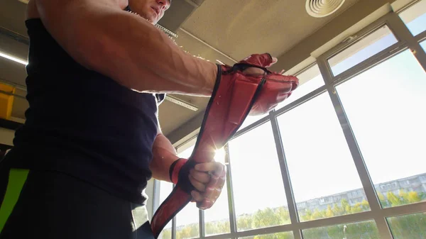 Muscular man bodybuilder putting on red training gloves — Stock Photo, Image