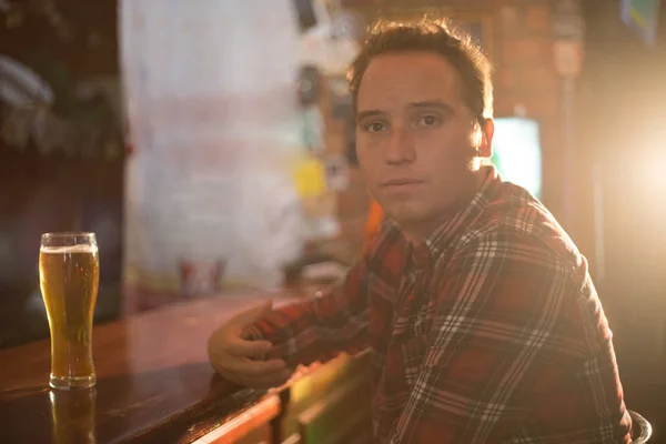 Thoughtful young man drinking beer at the bar