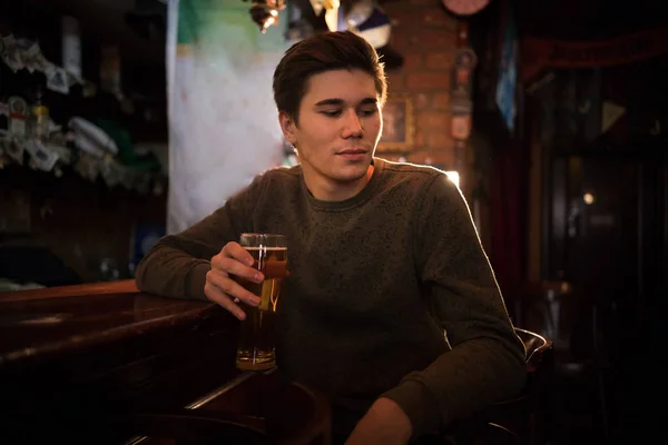 Jongeman bier drinken aan de bar, op zoek naar de kant — Stockfoto