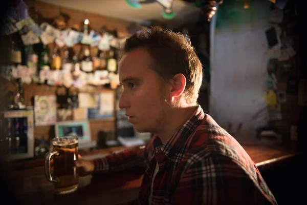 Nadenkende jongeman aan de bar met een pint bier — Stockfoto