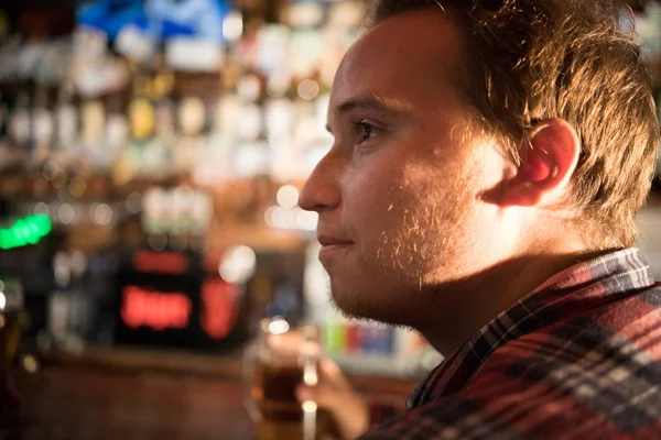 Продуманий молодий чоловік п'є пиво за барною стійкою — стокове фото