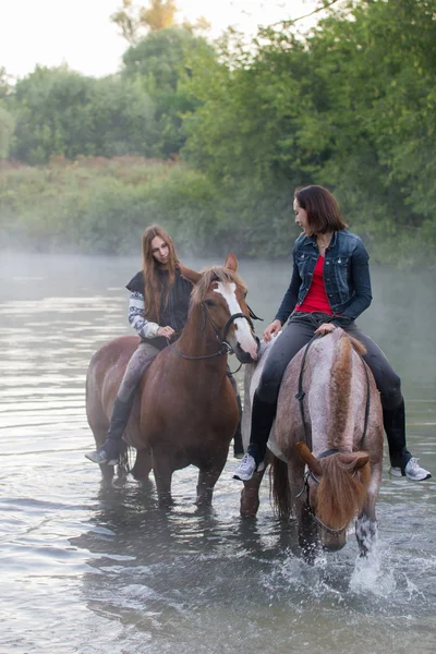 Deux jeunes femmes à cheval restent dans l'eau. Brouillard — Photo