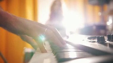Tekrarlama. Oynama ve baş ve bir adam klavyelerde sallayarak ifade kız davulcu. Elinden davul için odak. Arka ışık