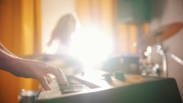 Herhaling. Meisje spelen op drums en een kerel op keyboards. Focus op handen. Achtergrondverlichting — Stockvideo