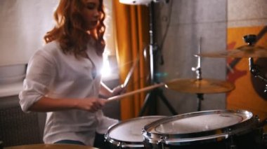 Tekrarlama. Kızıl saçlı kız üzerinde bateri çalıyor. Ağır çekim. Davulda odaklanmak