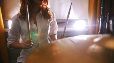 Tekrarlama. Kızıl saçlı kız üzerinde bateri çalıyor. Ağır çekim. Davulcu odaklanmak