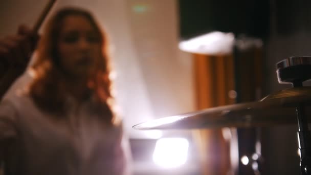 Wiederholung. Das rothaarige Mädchen spielt Schlagzeug. macht und stoppt die Vibration der Trommelplatte in Zeitlupe. Schlagzeug im Fokus — Stockvideo