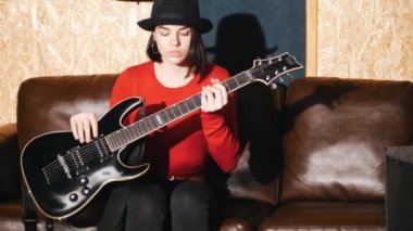 Bir kanepe ve gitar çalmaya başlar güzel kız oturur