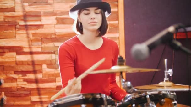 Meisje in zwarte hoed speelt enthousiast de drums — Stockvideo