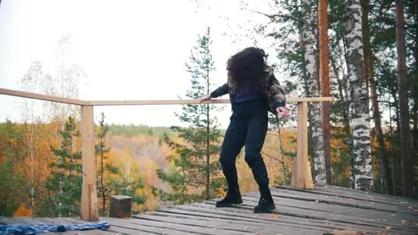 Feliz joven bailando en la plataforma. Cabello volador. Bosque en el fondo. Movimiento lento — Vídeo de stock