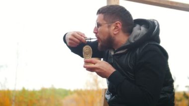 Açık havada ve konserve yemek bir bıçak ile bir adam oturuyor