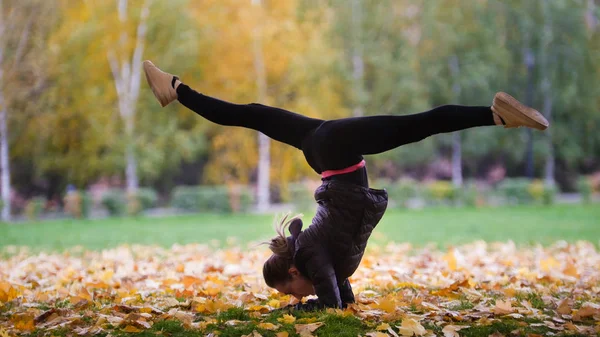 Kız jimnastikçi stand sonbahar park ellerinde performans — Stok fotoğraf