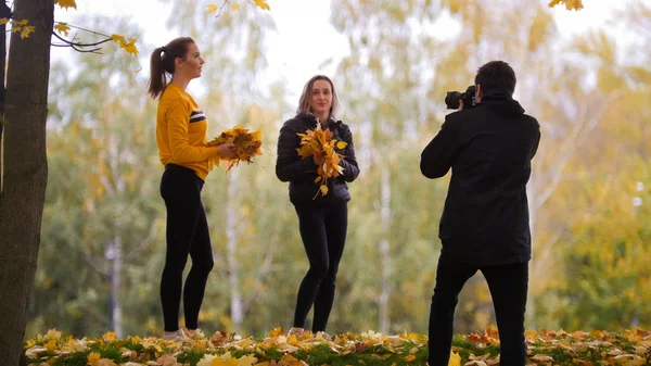 Akrobatické holky pózování před fotografem, drží žluté listy. — Stock fotografie
