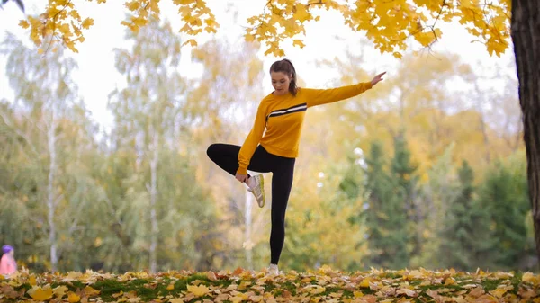 Dívka v svetr dělá akrobatické stojí. Gymnastka na školení. — Stock fotografie