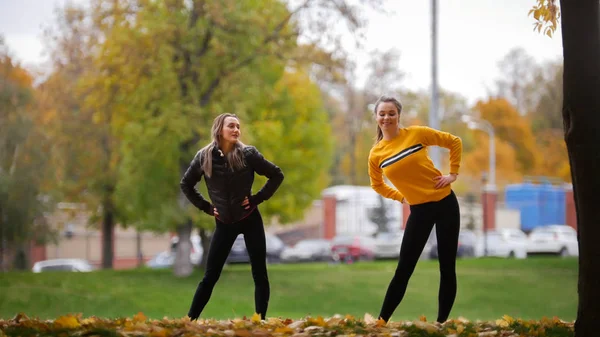 Meninas sorridentes aquecendo do lado de fora antes de treinar no parque . — Fotografia de Stock