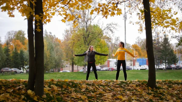 Akrobatické dívky oteplování až venku před tréninkem v parku. Ruce do stran — Stock fotografie