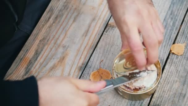 De handen van een man opent een ijzeren pot omhoog met een mes — Stockvideo