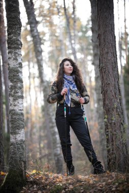 Kuzey yürüyüşü. Bir güz kıvırcık saçlı mutlu kadın portresi. Güneşli sonbahar parkta eğleniyor gülümser ve neşeli genç kadın.