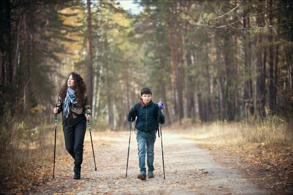 Caminar nórdico. El retrato del niño y la mujer rizada en otoño. Niño y mujer divirtiéndose en el soleado parque de otoño . — Foto de Stock