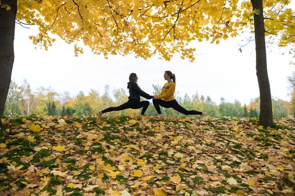 Podzimní fotografie sportovní žen, táhnoucí se v lese na ranní pozadí stromů. — Stock fotografie