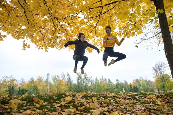 Podzimní fotografie sportovní žen skákání na ranní pozadí stromů v lese. — Stock fotografie