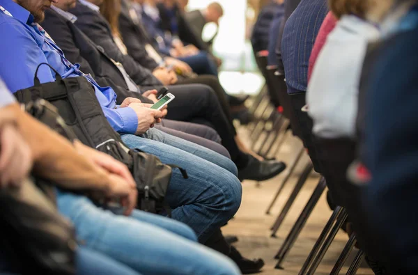 Gente seduta dietro alla conferenza d'affari. Seduto nel loro telefono — Foto Stock