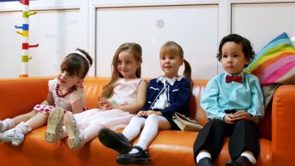 Четверо детей сидят в детской парикмахерской — стоковое видео
