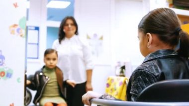 Küçük kız kümesi sandalyede moda ve kendi kendine aynada bak