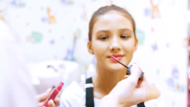 Maquillaje artista pinta a las niñas con lápiz labial crema — Vídeo de stock