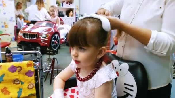 Kadeřník češe vlasy s vlasů mousse roztomilé dívce. Detailní záběr — Stock video