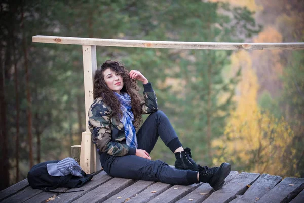 Fiatal nő ül egy platform, a háttérben az erdő — Stock Fotó
