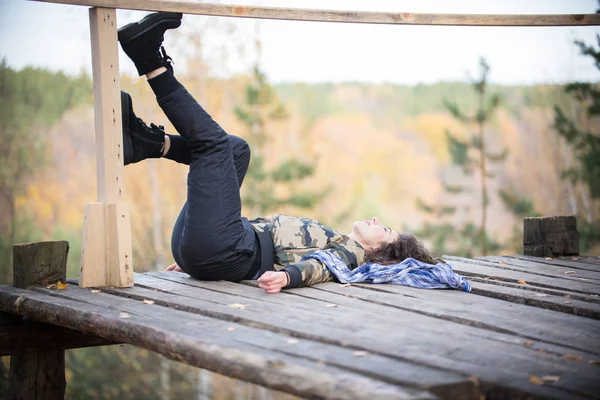 Молода жінка лежить на платформі на фоні лісу . — стокове фото
