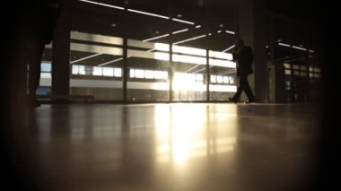 büyük pencere önünde yürüyen adam silüeti arka ışık