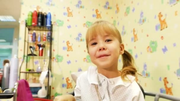 Barbearia infantil. Criança feliz sentada em poltrona . — Vídeo de Stock