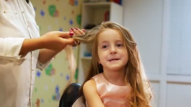 Friseur kräuselt lange Haare für kleines süßes Mädchen, mit elektrischem Lockenstab. Schiebereglerschuss — Stockvideo
