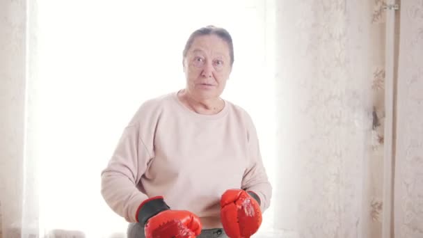 Portrait o old senior woman boxing in front of window — Stock Video