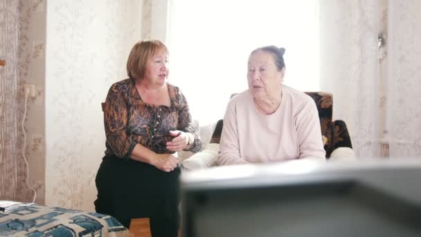 Zwei ältere Frauen fernsehen, kommentieren und miteinander reden — Stockvideo