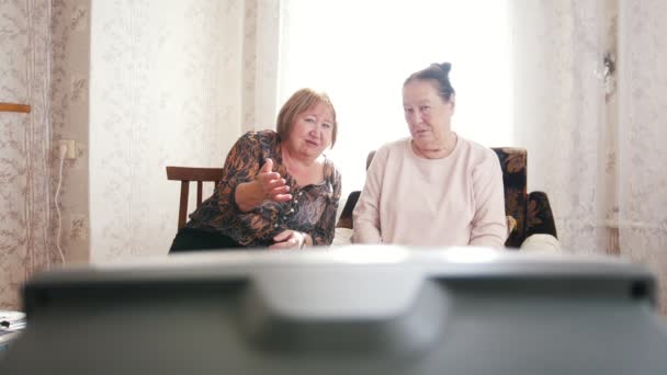 Två gamla kvinnor ser på Tv och prata med varandra — Stockvideo