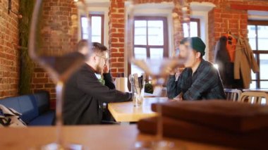 Bir restoranda bir masada oturan ve telefonda konuşurken iki adam