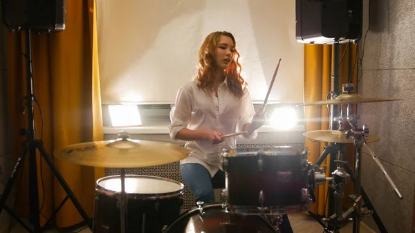 Rossa ragazza si siede dietro un tamburo set in il studio — Foto Stock