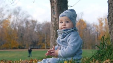 Sonbahar parkta çim üzerinde oturan küçük bir bebek