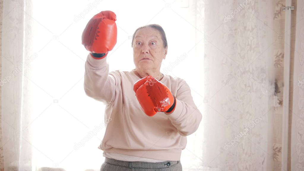 An old senior women boxing in red gloves, looking aggressive and funny