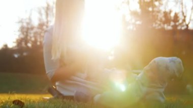 Genç Anne bebeğini sunset Bulvarında sonbahar parkta oynarken ile. Bebek çimenlerin üzerinde yatıyor. Mutlu bir aile