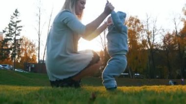 Sonbahar parkta oynarken küçük bebeği ile elbiseli Genç Anne. Mutlu bir aile