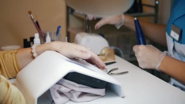 Manicura de hardware en una clínica de cosmetología.El especialista enciende la máquina — Vídeo de stock